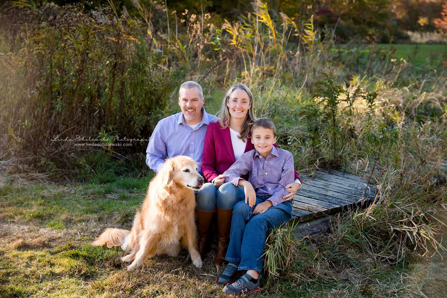 family of three with their dog at the park during fall for family photos at Bauer Park, CT Photographer