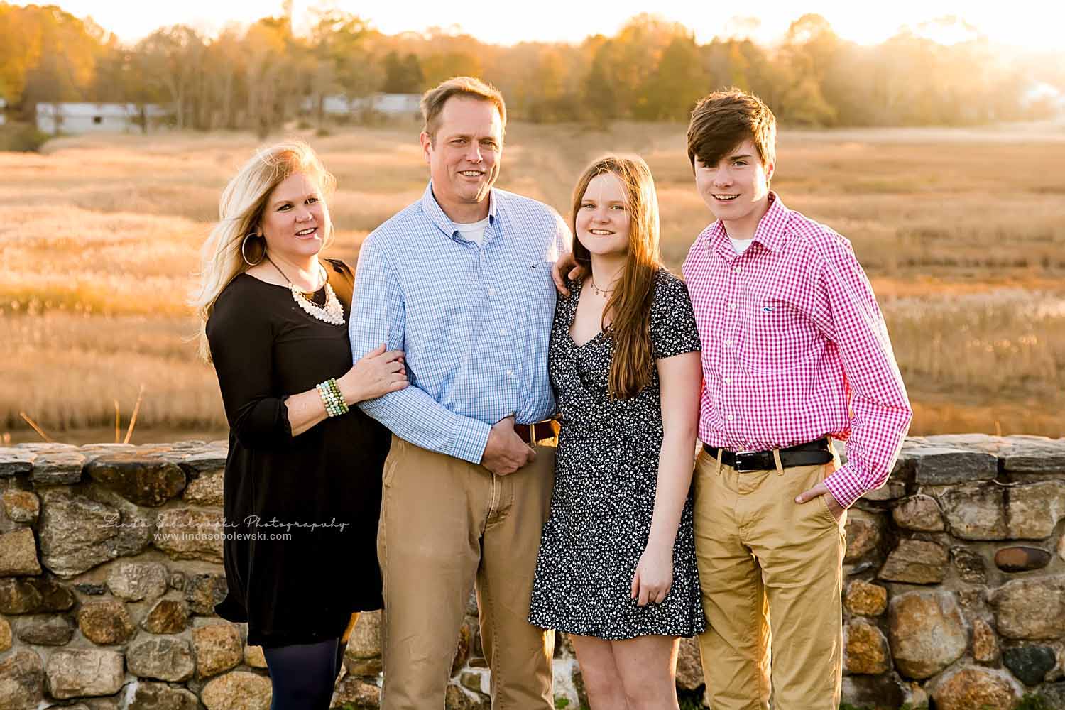 family of four taking fall family photos at Founder's Park in Old Saybrook, CT
