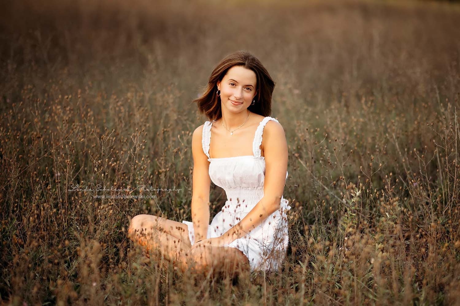 girl sitting in a field, Madison CT senior photographer