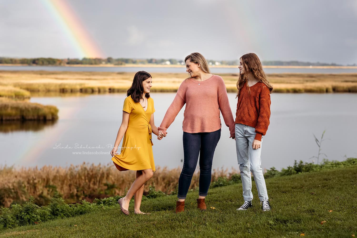mom and her two girls holding hands with a rainbow behind them, Old Saybrook CT Family Photoshoot
