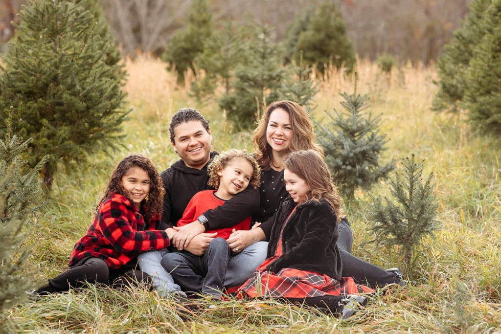 family of five sitting in a tree farm. Christmas Tree Farm Mini Session, Guilford, CT Photographer