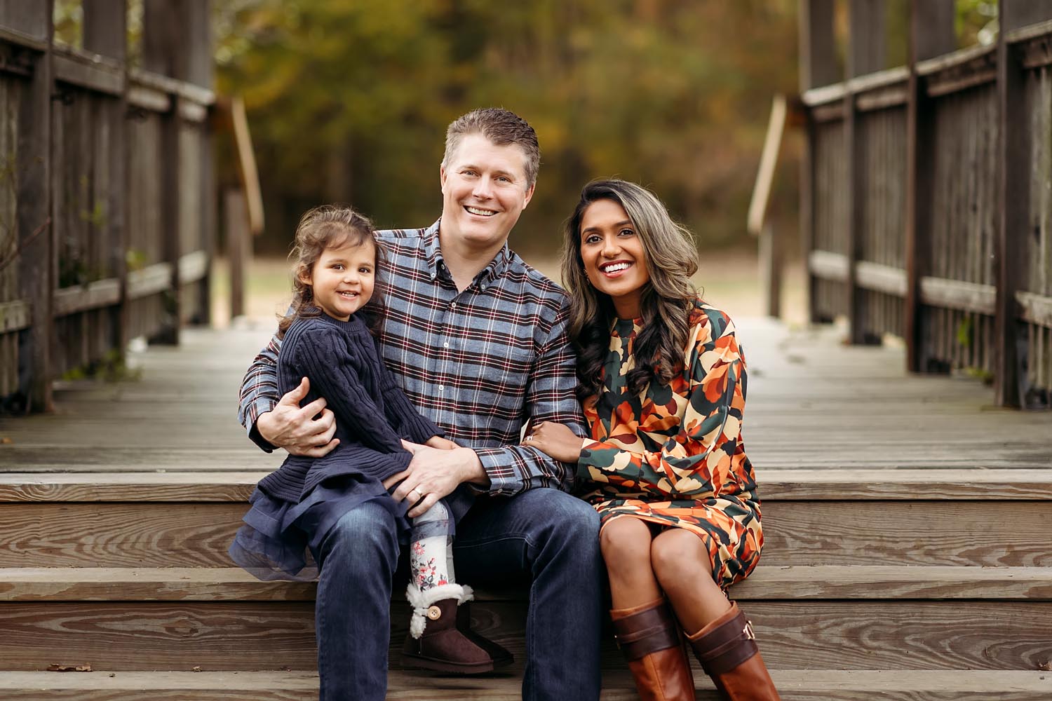 family of three sitting on a bridge for a fall mini-session, Madison CT family photographer