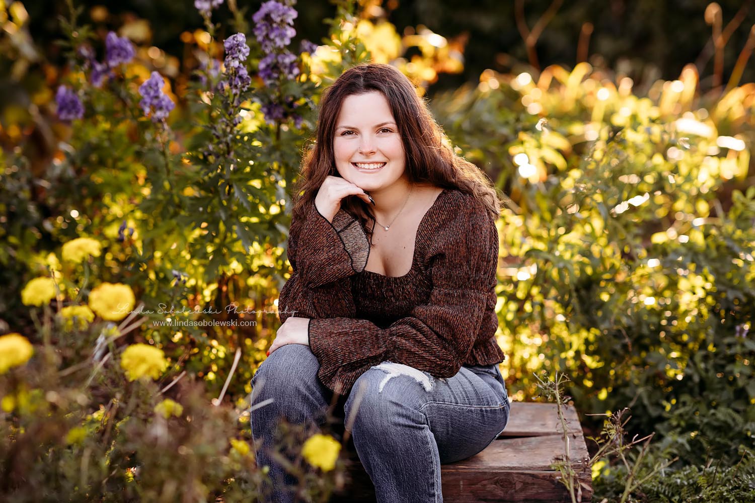 girl in brown sweater sitting in the flowers, Senior Photos at Harkness Memorial Park