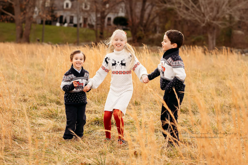 three siblings running around in the field. Photos at a Christmas Tree Farm, CT shoreline photographer