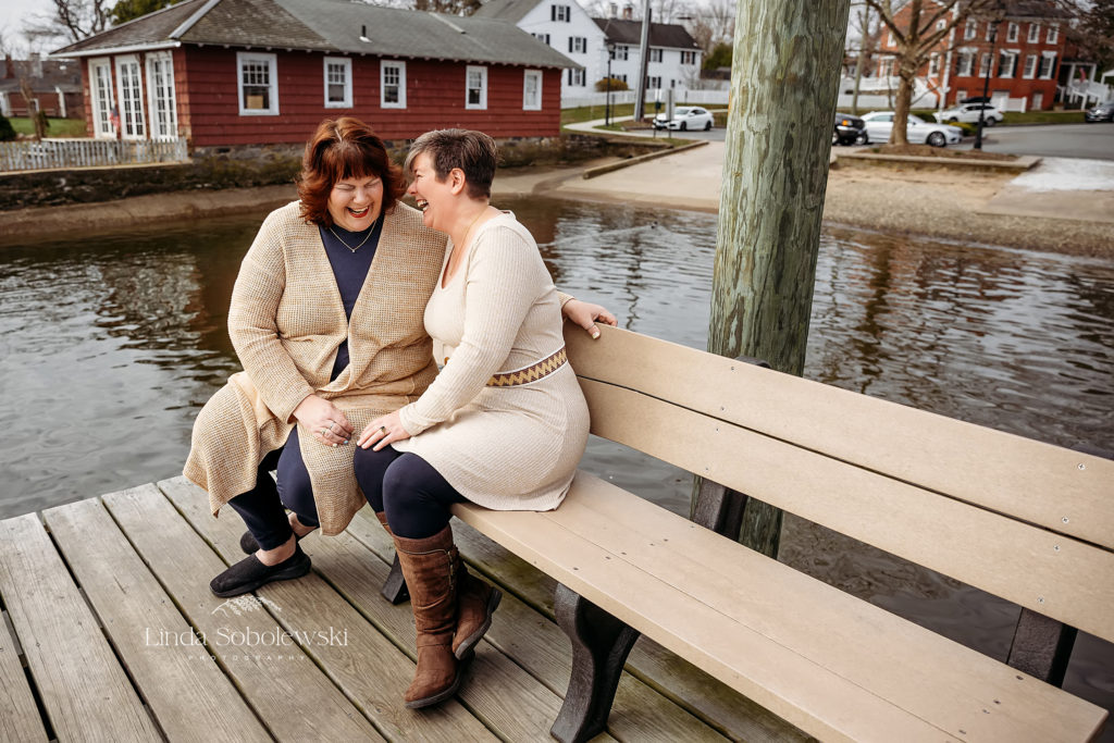 two sisters laughing on a bench, Essex, CT shoreline photography session