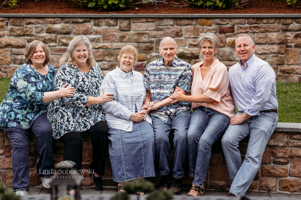 grandparents and adult children sitting on a stone wall for a large family photo session. CT Shoreline photographer