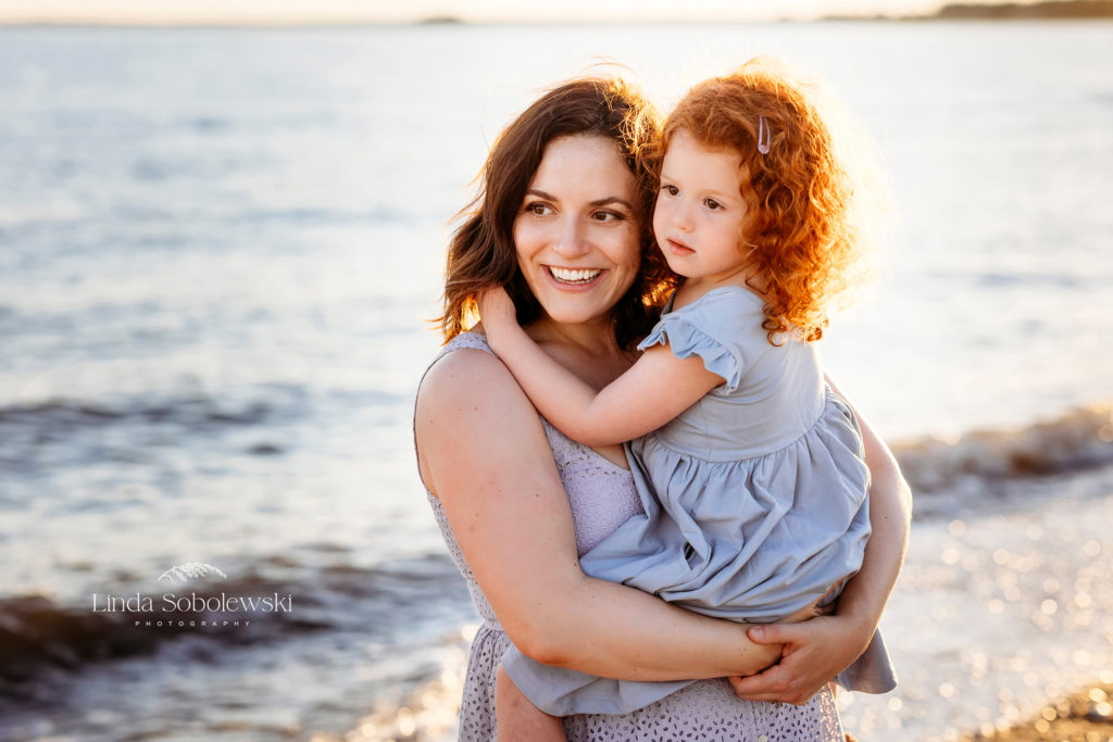 mom with blue dress holding her little girl at the beach, CT Shoreline family photographer