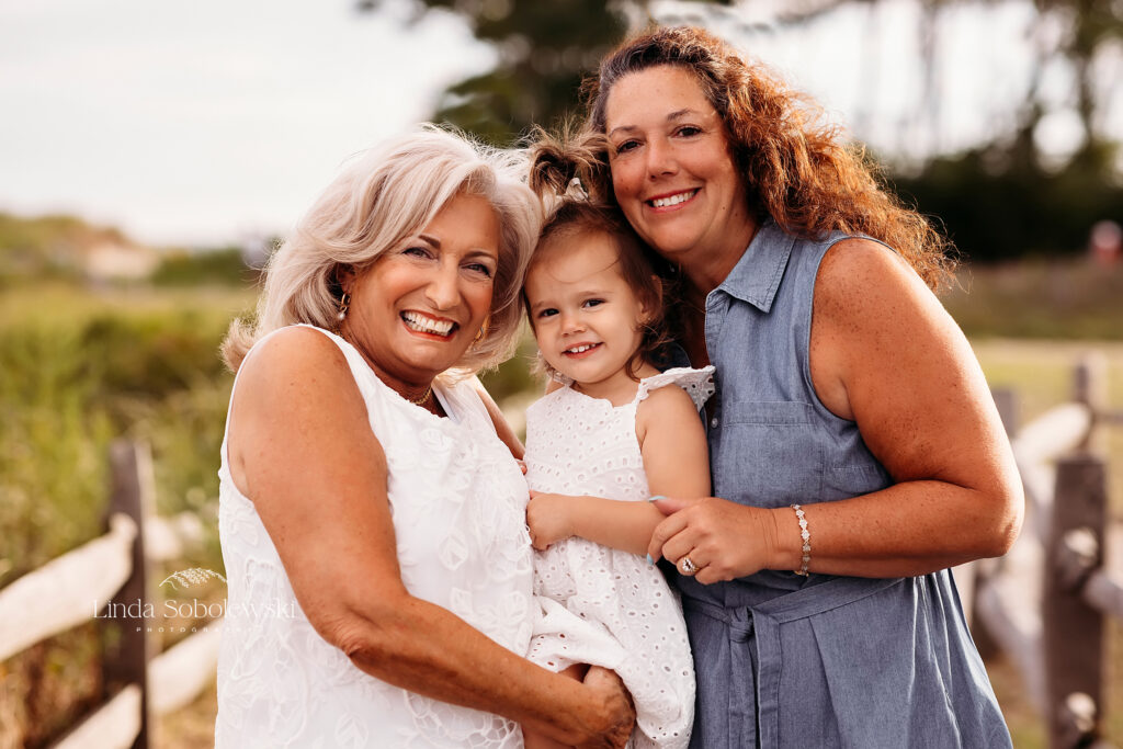 grandmothers holding their baby granddaughter. Big family photo session at the beach, CT shoreline photographer