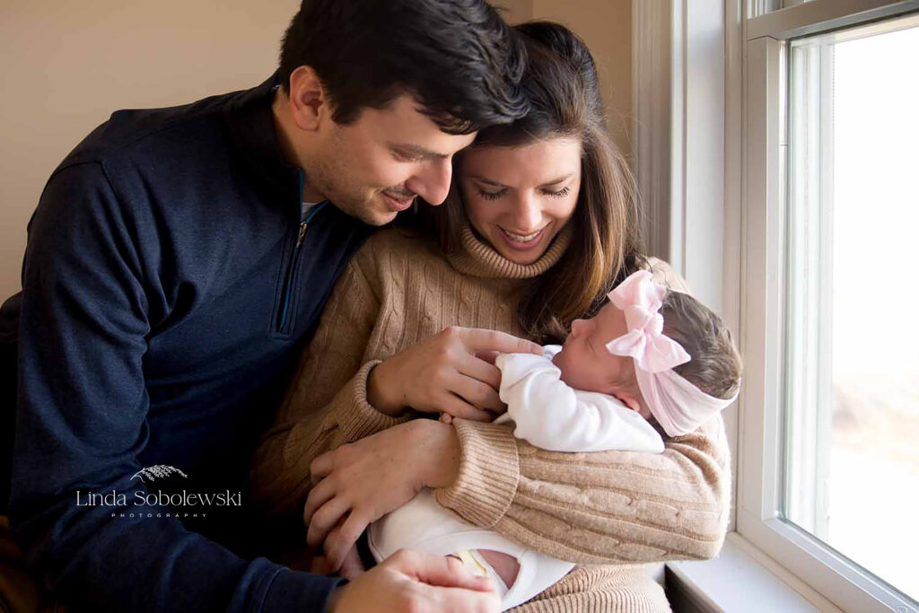 mother and father looking at their newborn baby, Old Saybrook Newborn photographer - why you should