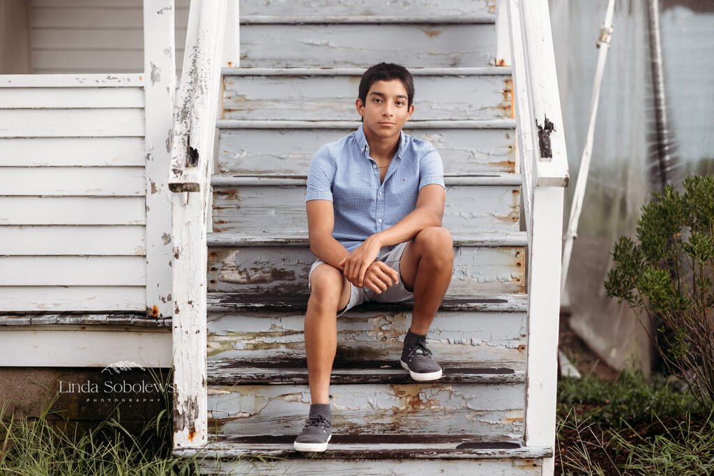teenage boy in blue shirt sitting on white steps, Old Saybrook CT Senior photographer