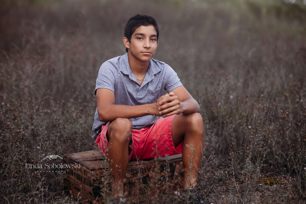 teenage boy in blue shirt sitting on a box, Madison CT Beach photographer