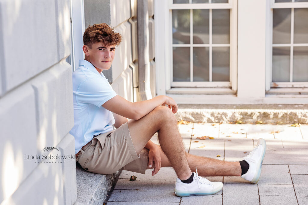 teenage boy in blue shirt sitting on a sidewalk, CT senior best friends session