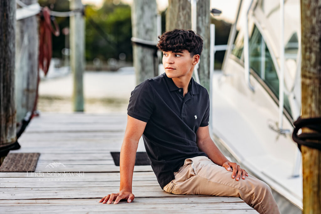 teenage boy in blue shirt, sitting on a dock, Madison CT senior photographer
