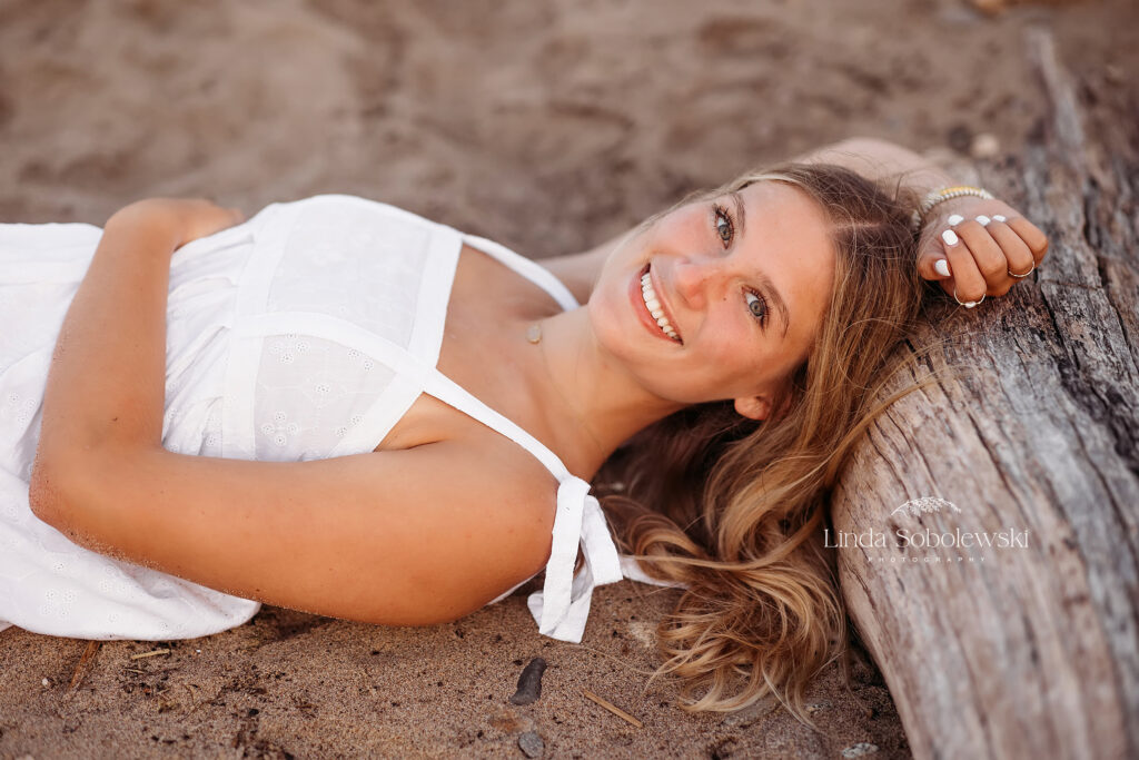 girl with blonde hair and white dress laying at the beach, Mercy High School SeniorSenior photographer