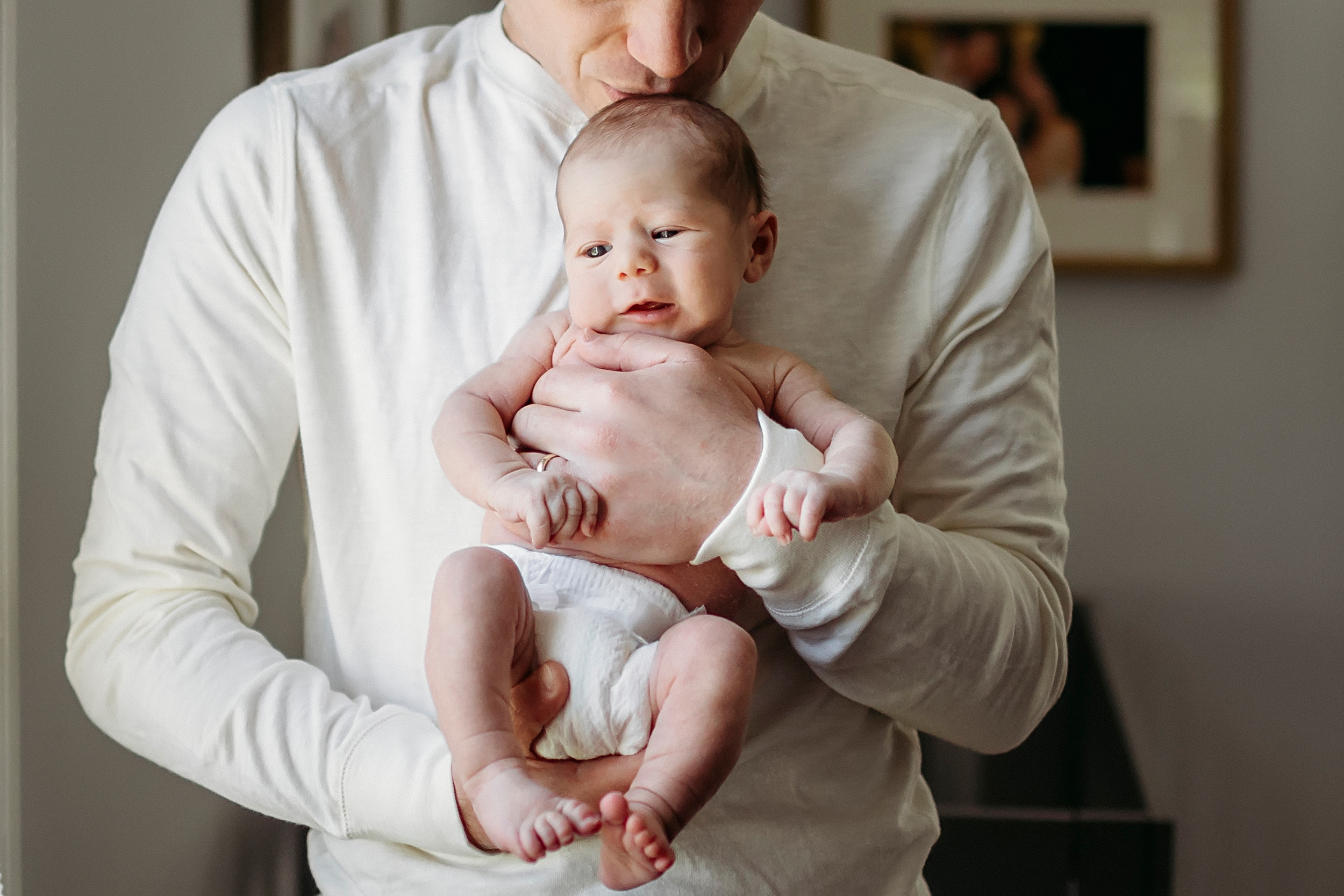 man in cream colored shirt holding a baby, Blog post for CT Baby photographer called What should dad wear to a lifestyle newborn session