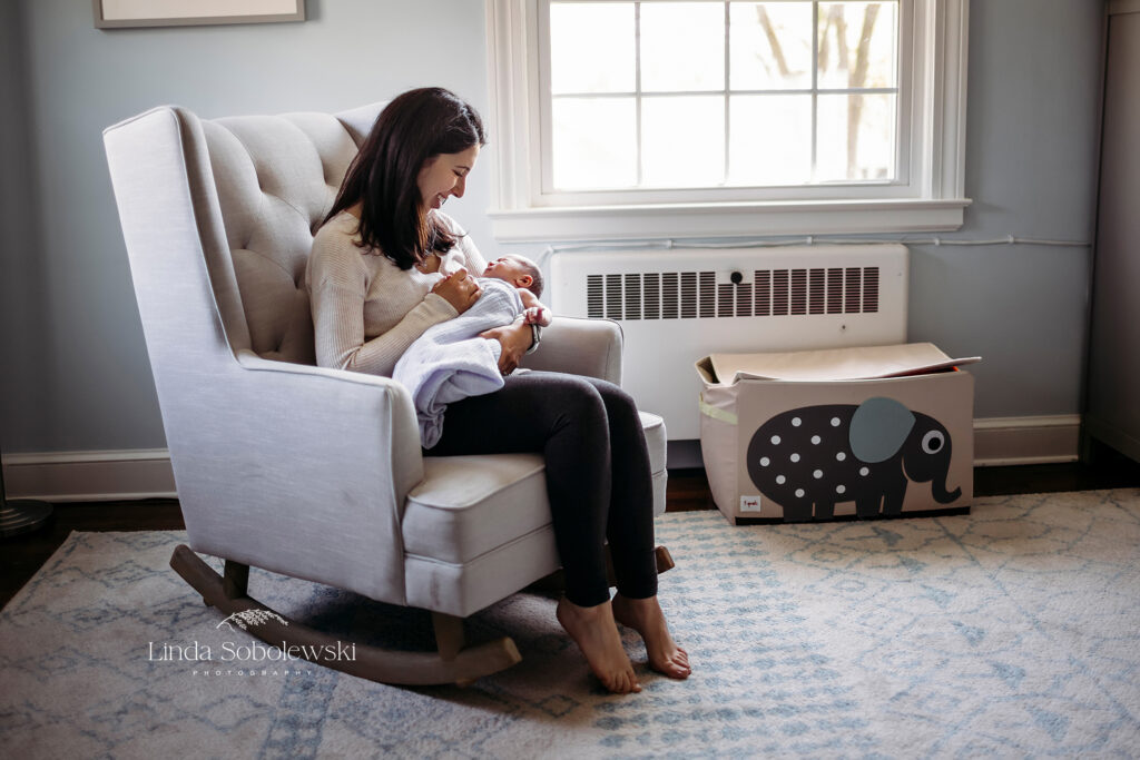 woman in a rocking chair, nursing her newborn baby, CT Newborn photographer blog post about what happens at a lifestyle newborn session