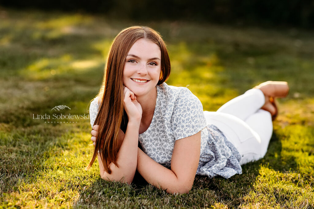 girl in blue top and white jeans laying on the ground, Old Saybrook CT Senior photographer