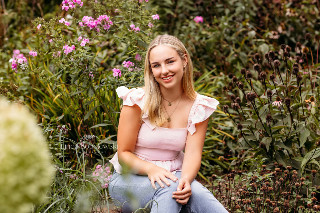 girl with blonde hair and pink tank top sitting in a garden, CT Shoreline best senior photographer at the Florence Griswold Museum