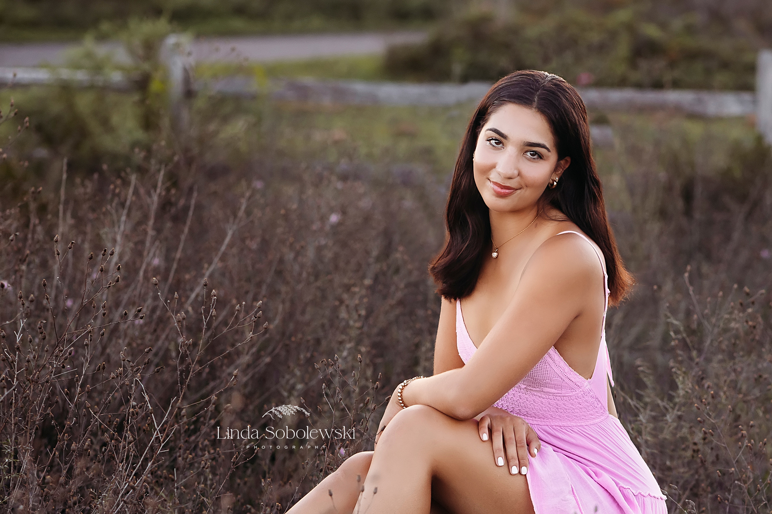 girl in pink dress sitting in a field, Madison CT High school senior girl photo shoot