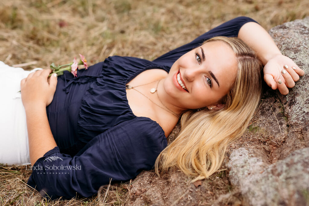 beautiful girl with blonde hair laying in the grass at the Florence Griswold Museum,Senior portraits with CT Best senior photographer