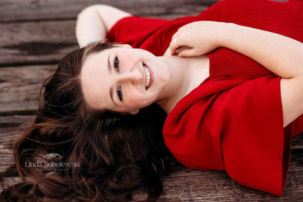 girl in red dress laying in the grass, Founders Park senior photo session