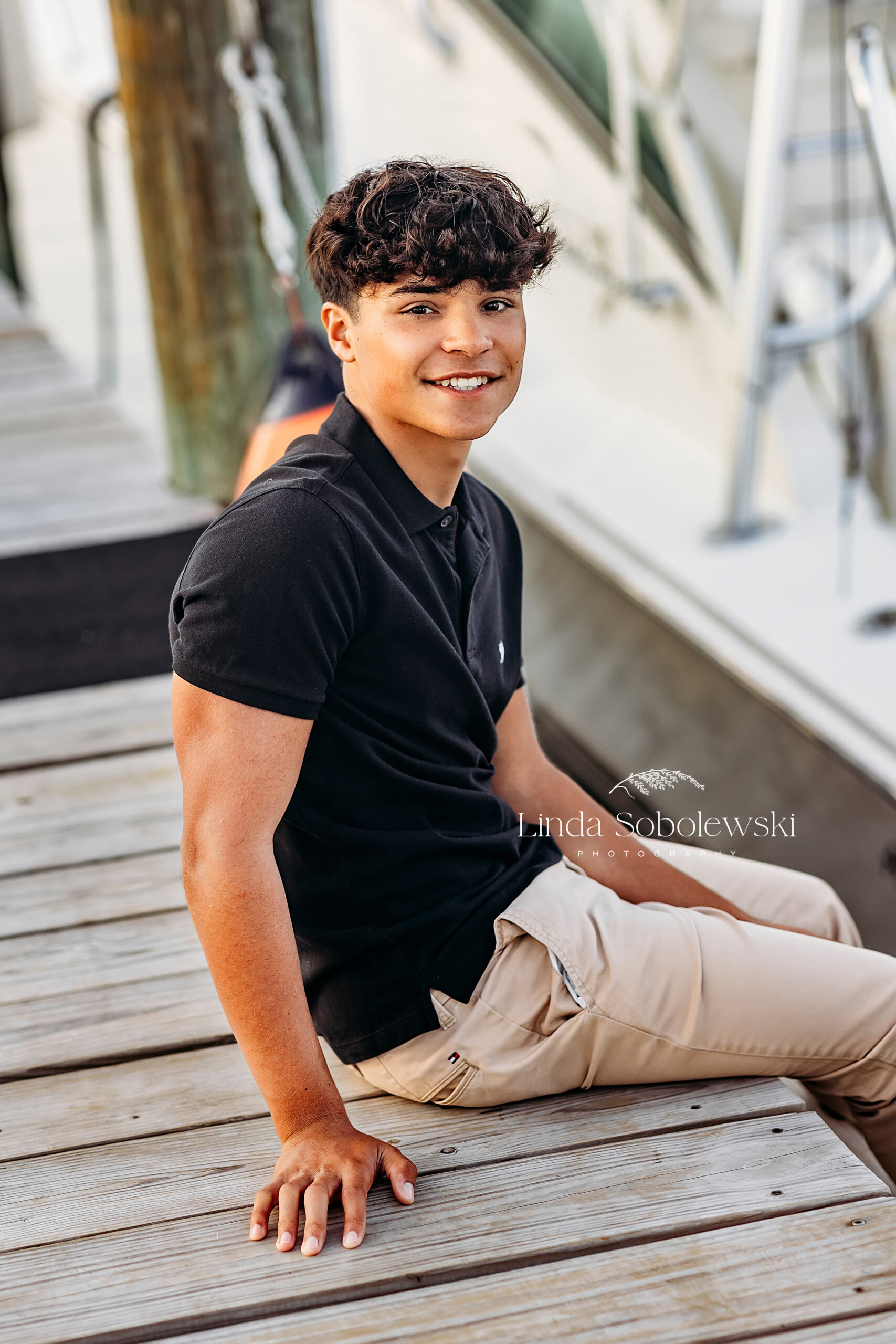 teenage boy in navy shirt, getting his senior photos take on a boat, CT Shoreline senior photographer