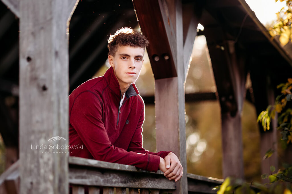 teenage boy in red sweater leaning against a bridge railing, Old Saybrook Senior photographer
