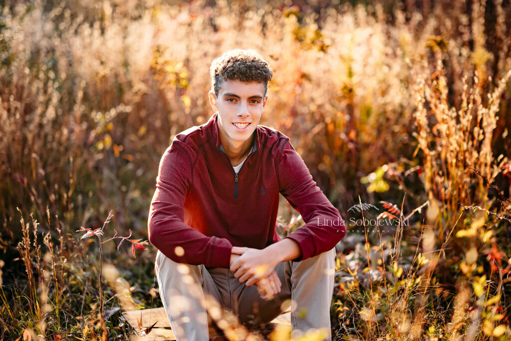 senior boy in sweater sitting in a field, CT Senior boy photography session