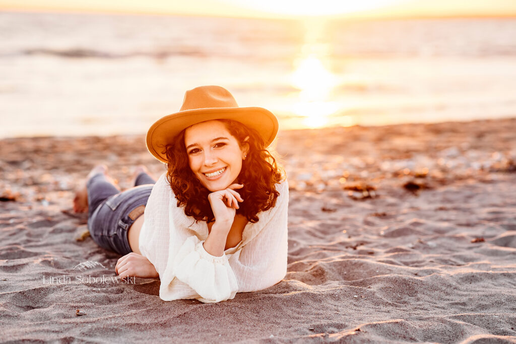 girl in white top and hat, sitting in grass at the beach, CT Beach photographer