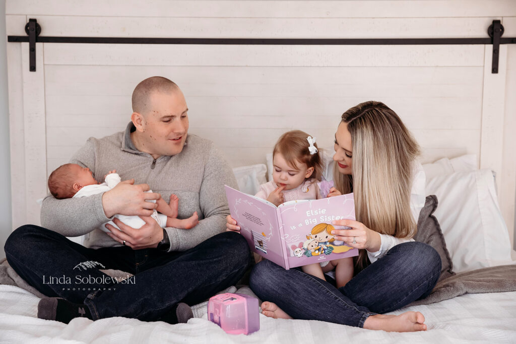 family of four sitting on their bed together, Newborn Photographer in Westbrook CT