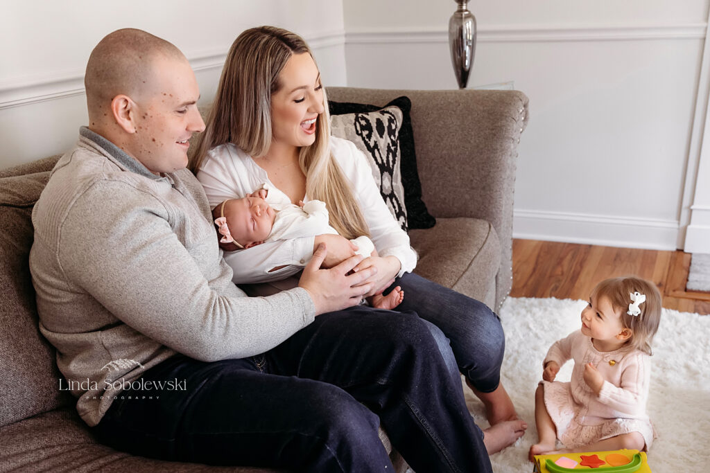 mother and father holding their newborn baby in their living room, Branford CT photographer