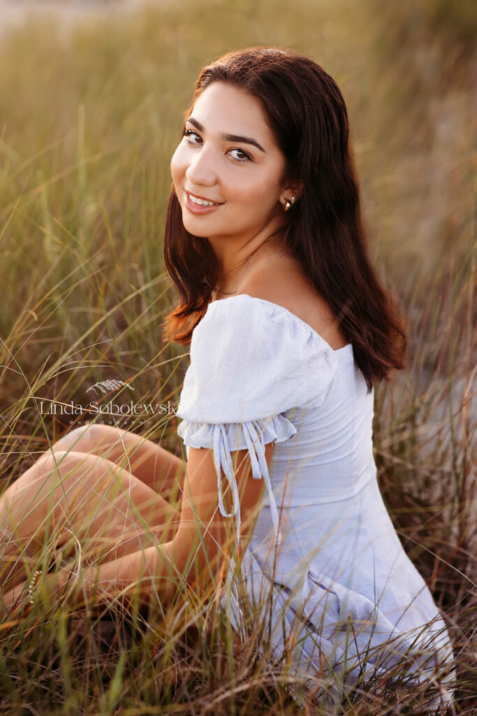 Girl in blue dress sitting in the grass at the beach, CT Best Senior Photographer