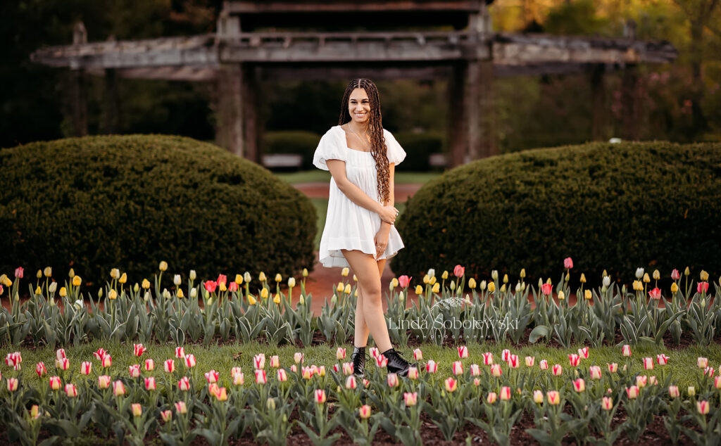 teenage girl in white dress and long black braids standing in a field of tulips at Elizabeth State Park, West Hartford CT Senior photographer