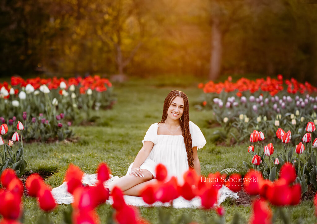 girl in white dress sitting in a field of red tulips, CT Shoreline Best Senior Photographer