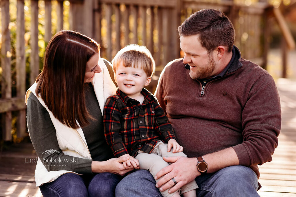 little boy with blonde hair sitting between his parents. Beautiful Family Photos in CT