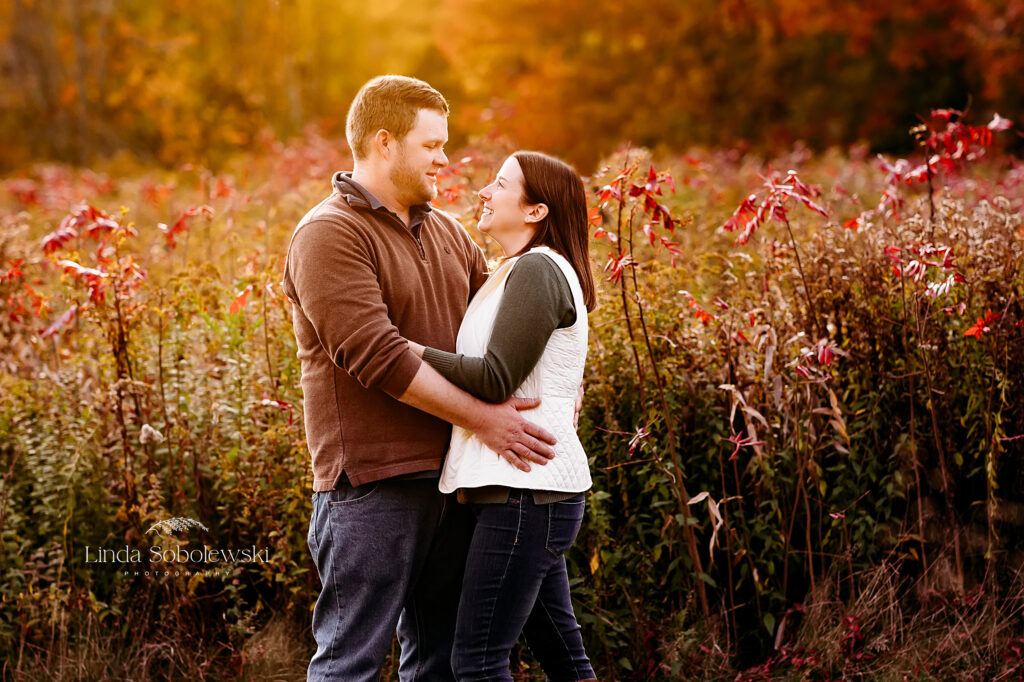 husband and wife looking at each other in a fall park, Guilford CT Family photographer