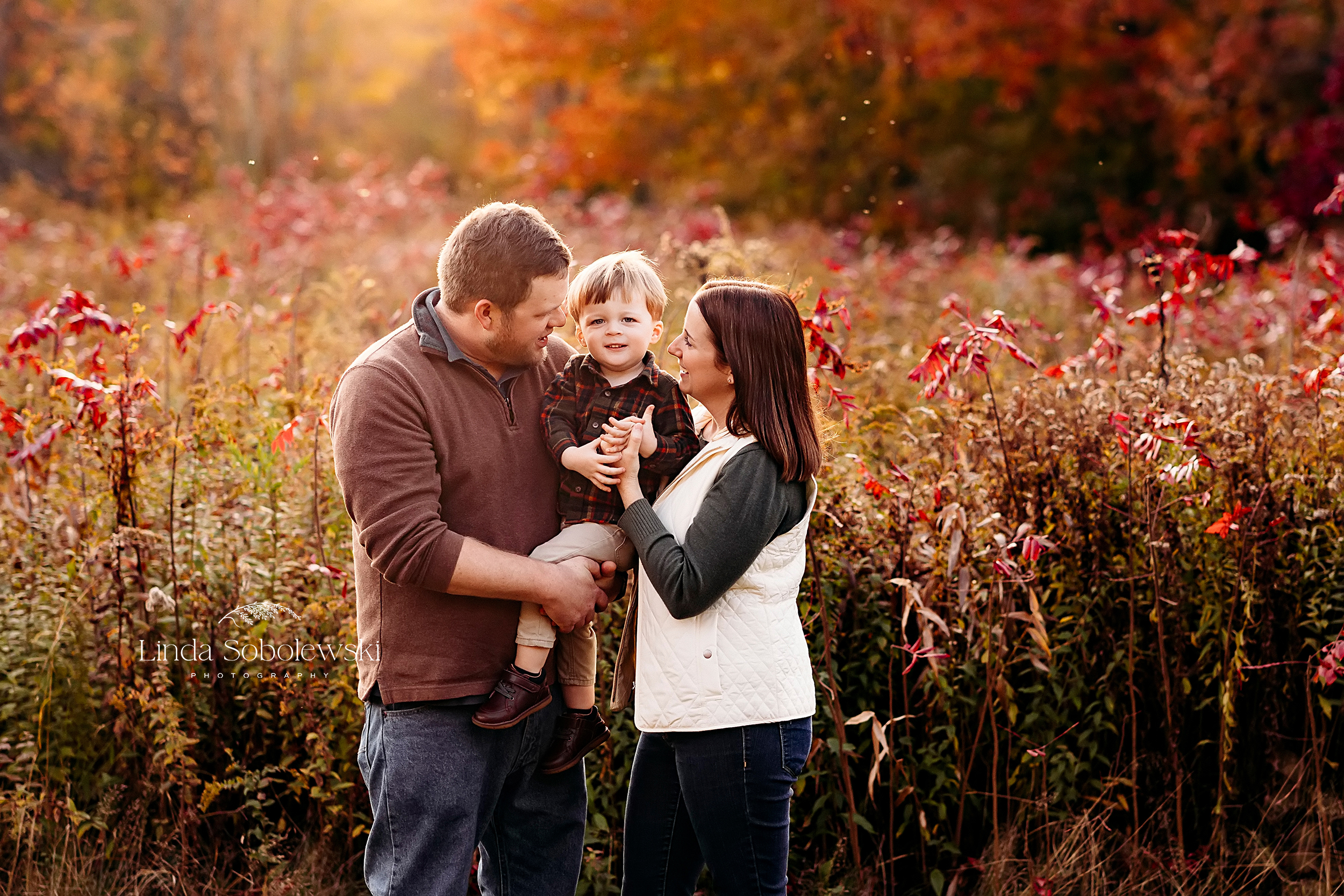 family of three in a park during the fall, CT Family Photographer
