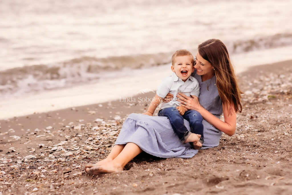 mom in blue dress sitting on the beach with her little boy, Guilford CT family photographer