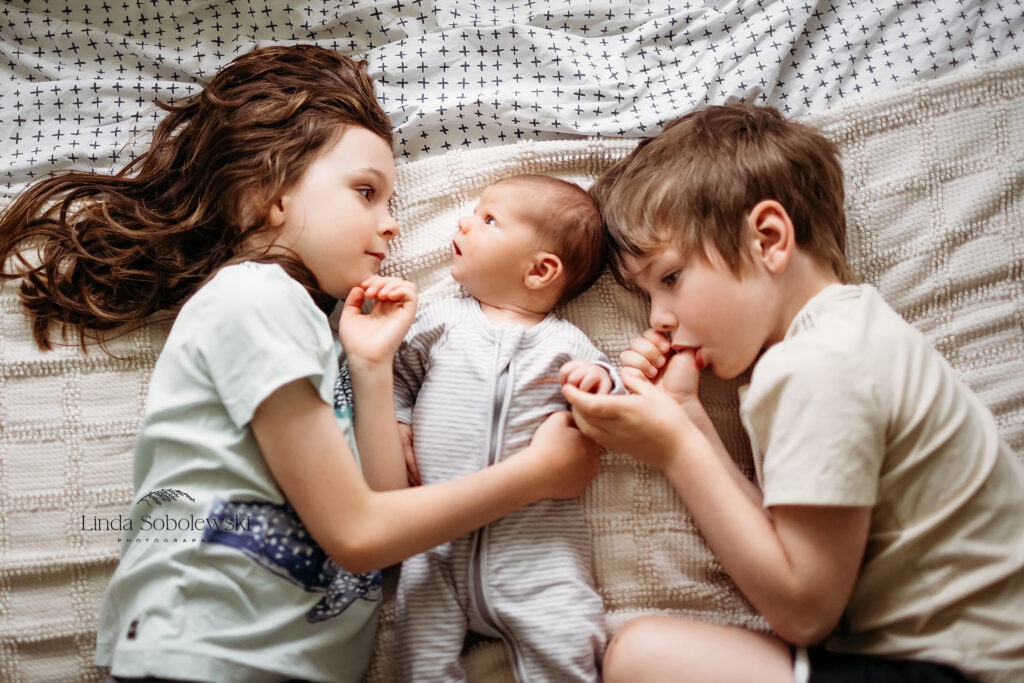 two brothers laying in bed with their newborn baby brother, Newborn photographer in Chester CT