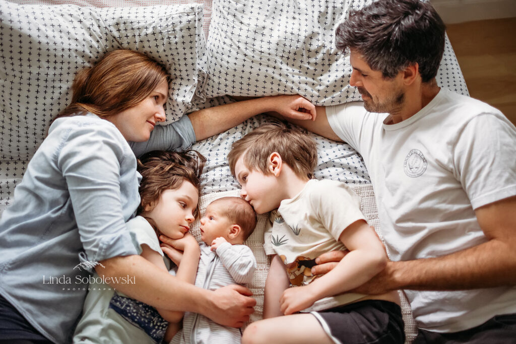 family with new baby laying together in bed, Newborn Session in Chester CT