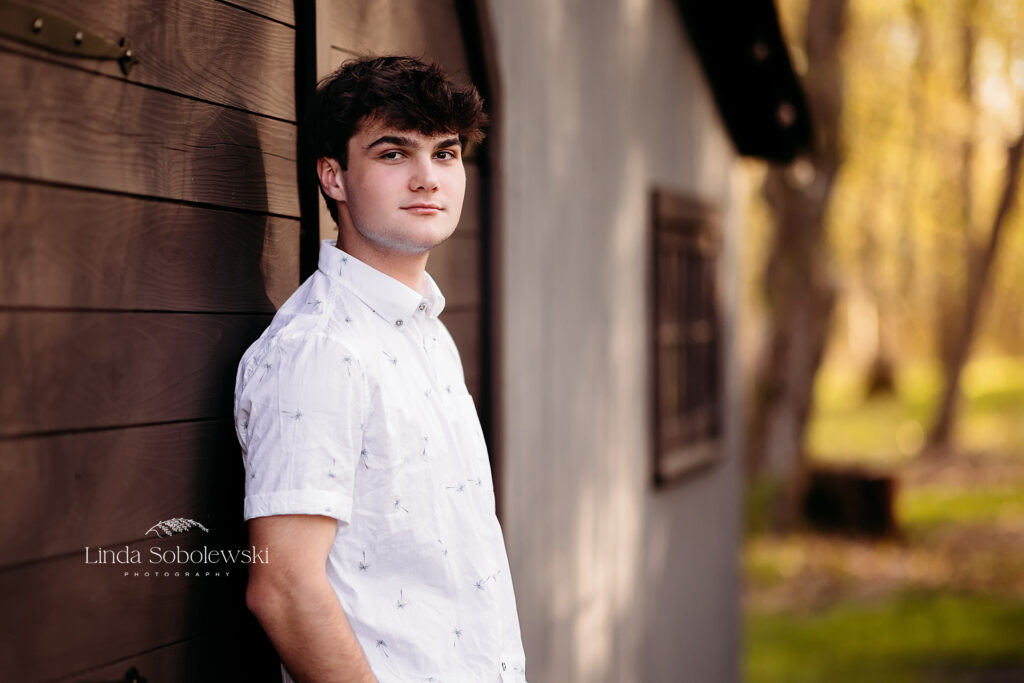 boy in white shirt standing against a barn, Madison, CT photo session