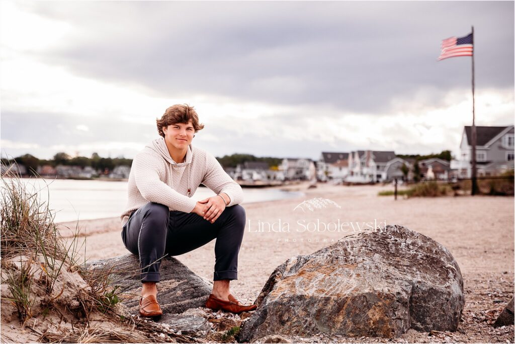 teenage boy in brown sweater sitting at the beach, High School Senior Boy photos, CT photographer
