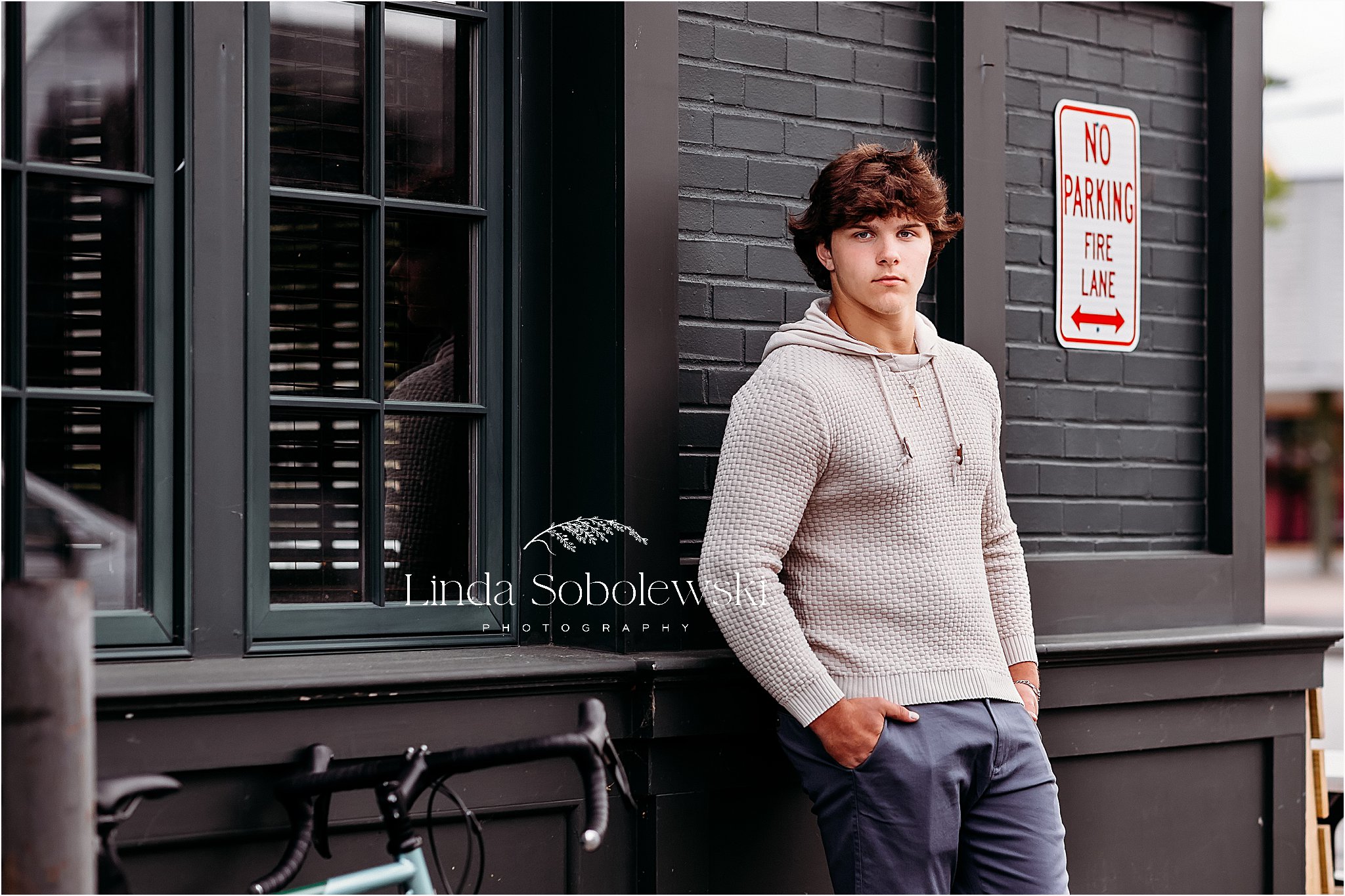 teenage boy in brown sweater leaning against a green building, High School Senior Boy photo session