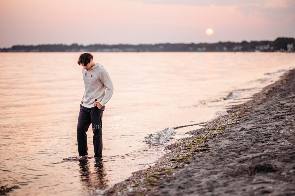 teenage boy walking in the water at the beach, Westbrook CT senior photographer