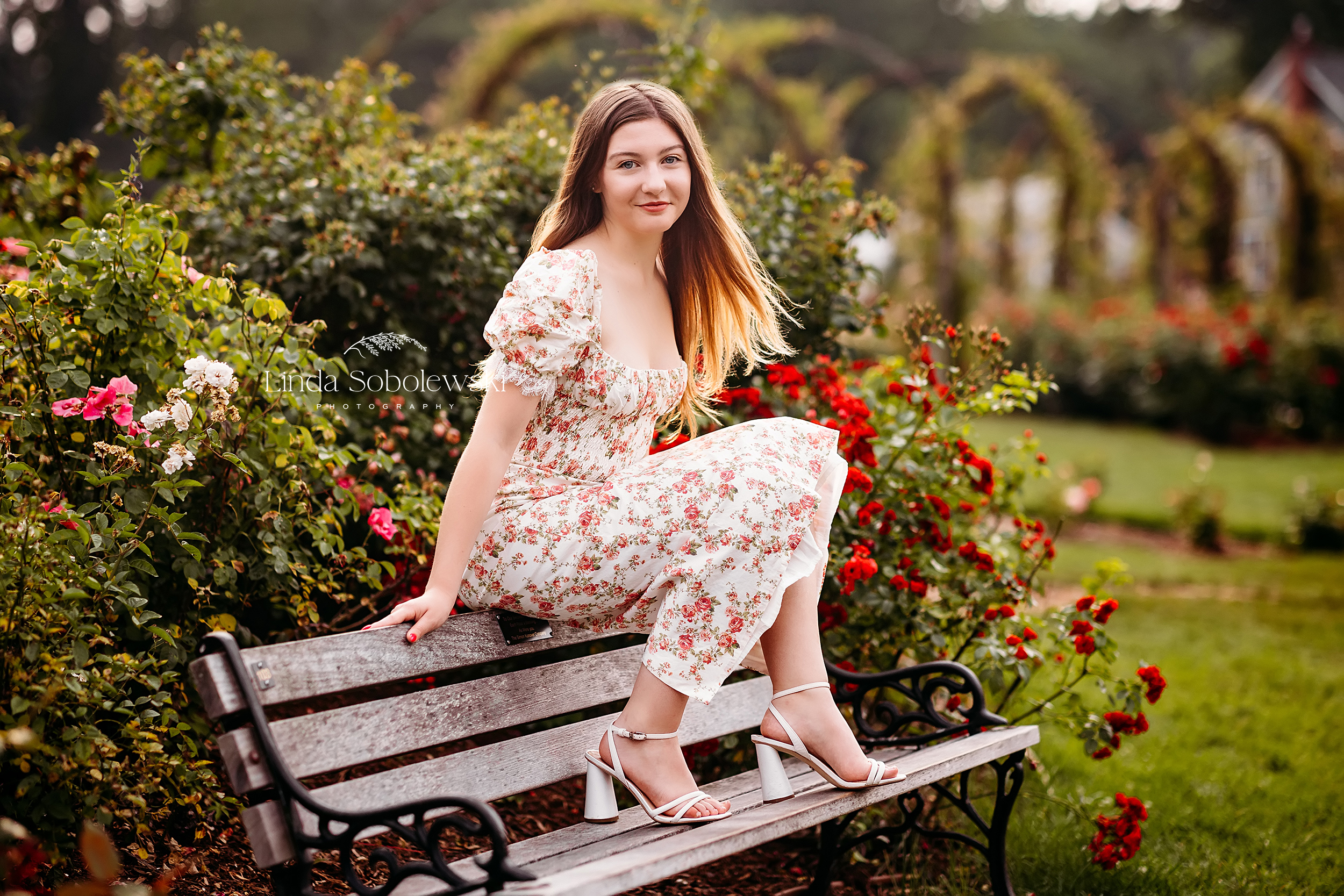 girl in floral dress sitting on a bench in a garden, CT Best senior photographer