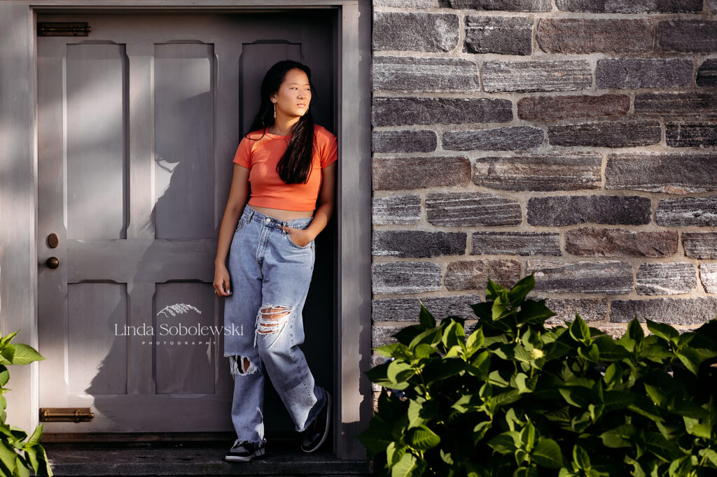 girl in orange shirt leaning against a wall, CT shoreline photographer