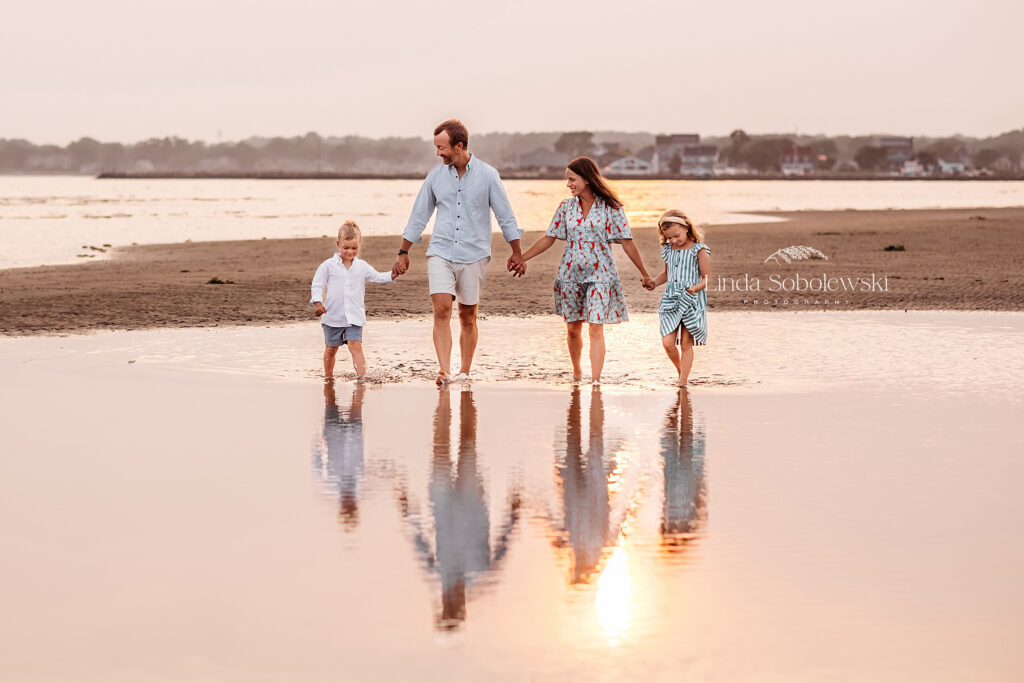 family of four walking on the beach during a beautiful sunset, summer night petite sessions, 2023 with CT's best photographer