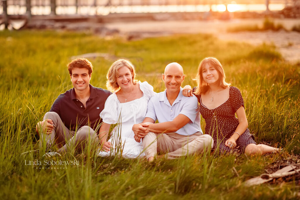 family of four sitting in the grass at the beach, CT Family photographer