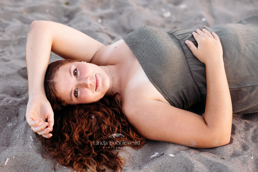 girl in green dress laying on the beach, Senior photos at hammonasset beach in Madison, CT