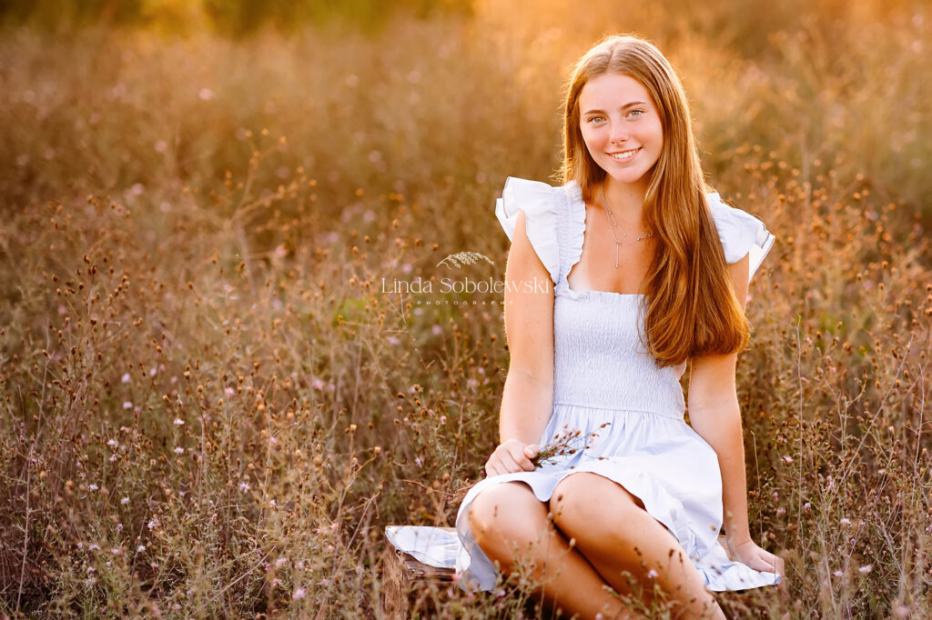 pretty girl in blue dress sitting in a field, Madison, CT photographer